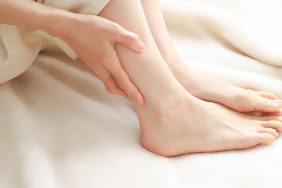 気温差が激しいことによって血流のリズムが乱れ、足の不調を感じる女性のイメージ