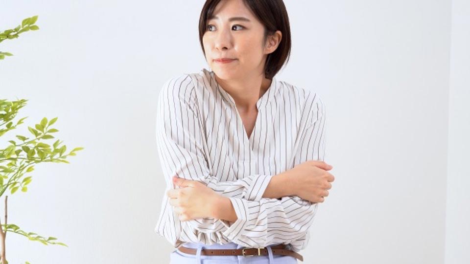 外の熱気と室内の空調による冷えのギャップで不調を感じる女性のイメージ
